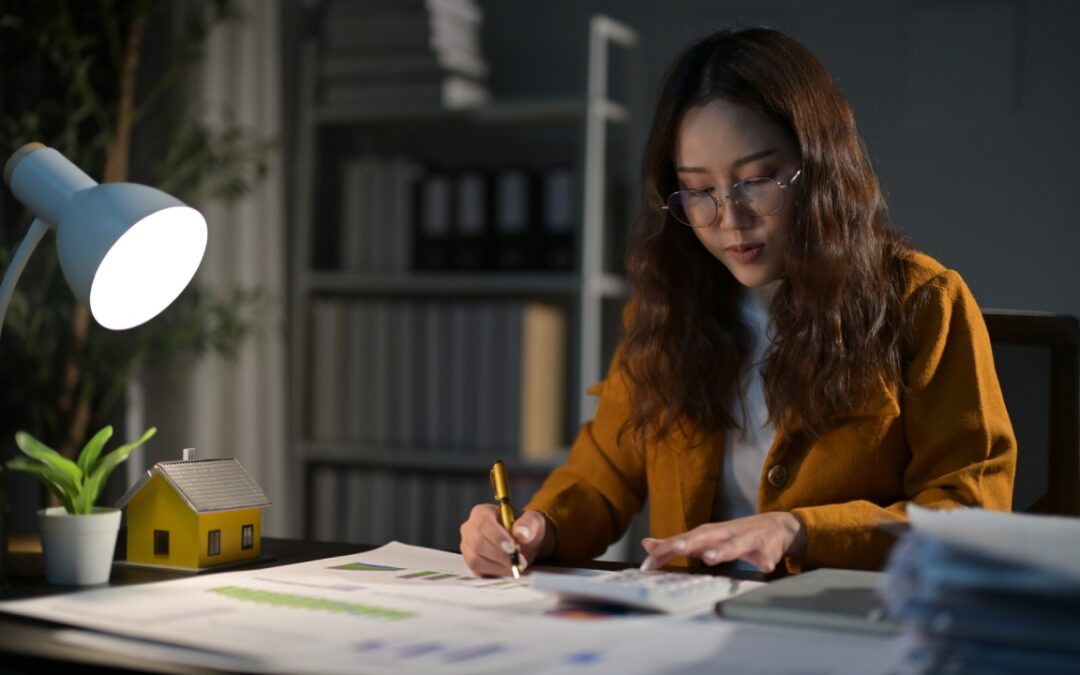 A professional young woman working late at night. She is analyzing graphs and charts while making calculations.