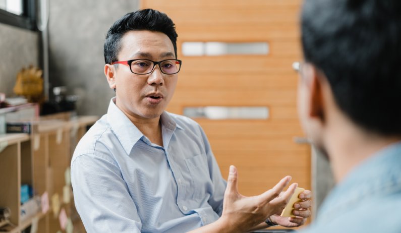A worker sitting in a corporate office and having a serious conversation with a fellow coworker to create an understanding.